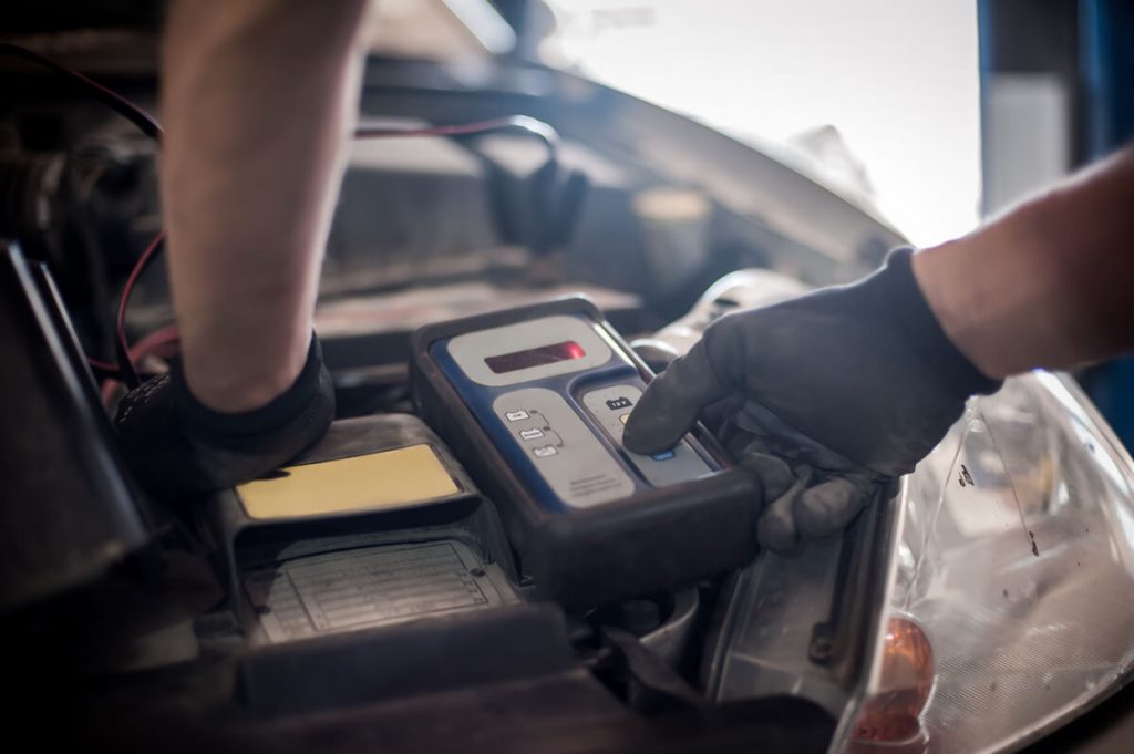 Auto mechanic using battery tester