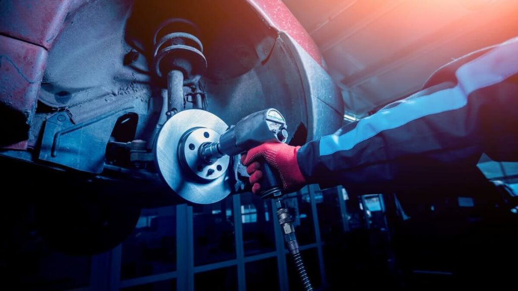 Auto mechanic using air impact wrench