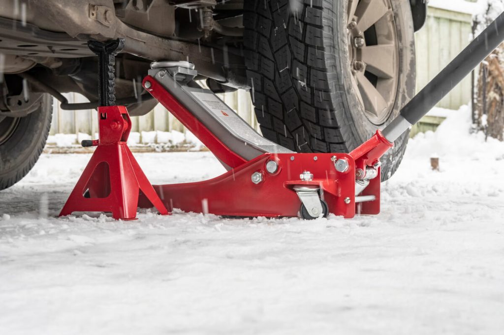 Floor jack and jack stand under a truck